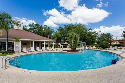 a pool at a resort with chairs and trees at Your VIP Home near Disney 25107 in Kissimmee