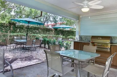 a patio with a table and chairs and umbrellas at Your VIP Home near Disney 25107 in Kissimmee