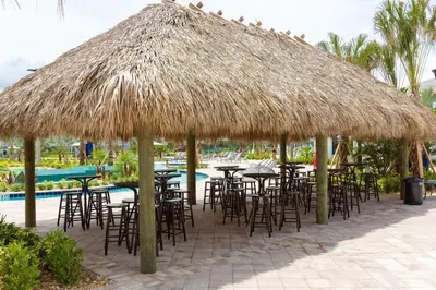 a group of tables and chairs under a straw umbrella at Amazing 4BDR with pool near Disney - 4914 in Kissimmee