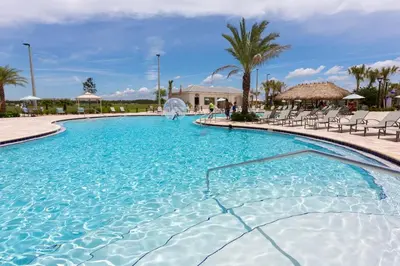 a large swimming pool with chairs and palm trees at Amazing 4BDR with pool near Disney - 4914 in Kissimmee