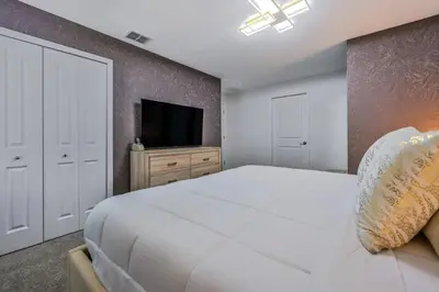 a bedroom with a large white bed and a flat screen tv at Casa Temática c/ Piscina no Storey Lake in Kissimmee