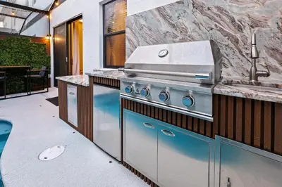 a outdoor kitchen with a grill and a pool at Luxury Stay Walk to SeaWorld Minions Room in Orlando