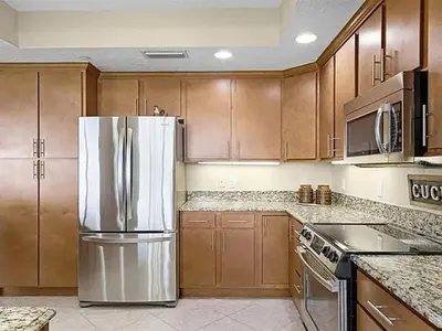 a kitchen with wooden cabinets and a stainless steel refrigerator at Spacious Lakefront Condo in Kissimmee in Kissimmee