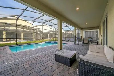 a patio with a couch and a swimming pool at Villa Luxuosa 9Q c/ Piscina Privativa e Temas in Kissimmee