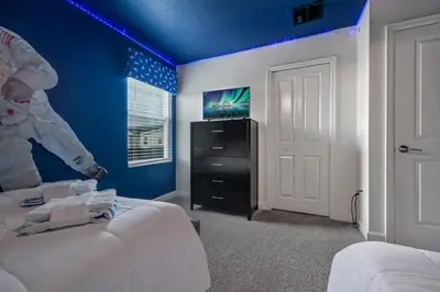 a bedroom with blue walls and a bed and a tv at Villa Luxuosa 9Q c/ Piscina Privativa e Temas in Kissimmee