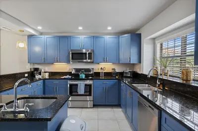 a blue kitchen with stainless steel appliances and blue cabinets at 14531 Damai in Orlando