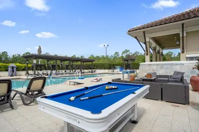 a pool table on a patio next to a swimming pool at 14531 Damai in Orlando