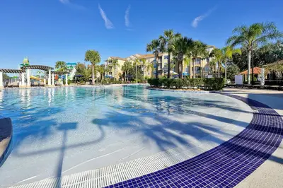 a swimming pool at a resort with palm trees and buildings at Spring Break Awaits Disney Close Pool Slides Fun in Orlando
