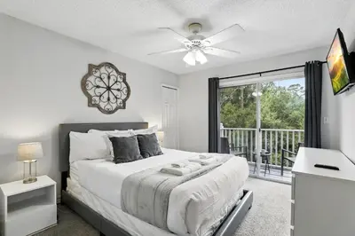 a bedroom with a bed with a ceiling fan and a balcony at Family Escape Near Disney Serene Retreat in Terra Verde Resort in Kissimmee