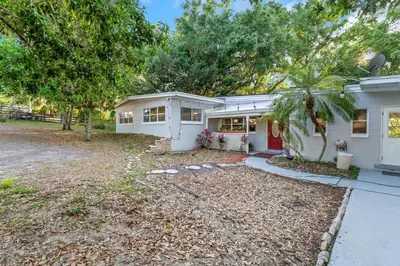 a white house with a palm tree in front of it at Orlando 3BR | Hot Tub + Parking + Pets in Orlando