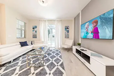 a living room with a white couch and a large tv at Casa c/ piscina privativa a 10 min da Disney in Kissimmee