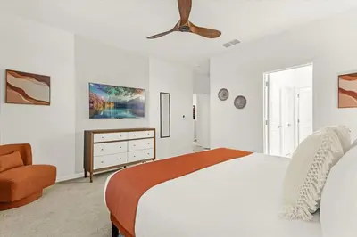 a white bedroom with a bed and a chair at Upstay Bella Vida Resort - Resort-Style 12BR Villa in Kissimmee