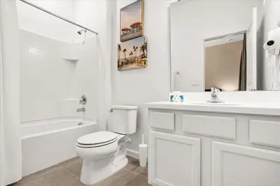 a white bathroom with a toilet and a sink at Upstay Bella Vida Resort - Resort-Style 12BR Villa in Kissimmee