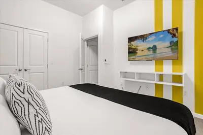 a bedroom with a white bed and a tv on the wall at Upstay Bella Vida Resort - Resort-Style 12BR Villa in Kissimmee