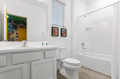 a white bathroom with a toilet and a sink and a tub at Upstay Bella Vida Resort - Resort-Style 12BR Villa in Kissimmee