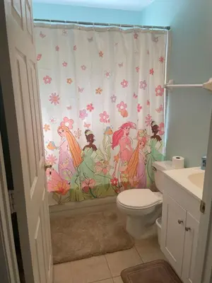 a bathroom with a shower curtain with mermaids at Plutospad in Orlando