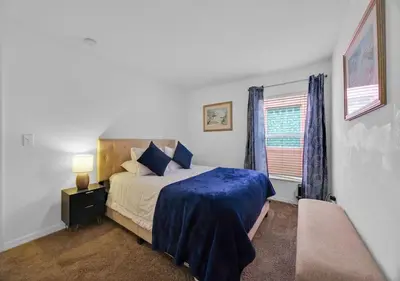 a bedroom with a bed with a blue blanket and a window at Spacious Emerald Home - Pool and Lanai Near Disney in Kissimmee