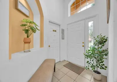 a hallway with a white door and two potted plants at Spacious Emerald Home - Pool and Lanai Near Disney in Kissimmee