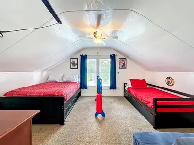 a attic room with two beds and a window at 1920s Rustic Cabin, 20 Min to Disney and Nightlife in Orlando