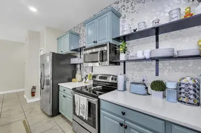 a kitchen with blue cabinets and a stainless steel refrigerator at Resort Fun Star Wars Toy Story Rooms Near Disney in Kissimmee