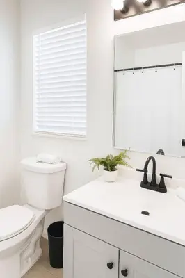 a white bathroom with a toilet and a mirror at Beauty 4 miles to Disney 3Br 2Ba Pool Home in Kissimmee