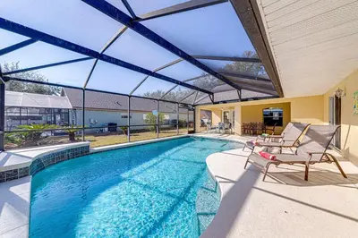 a swimming pool with two chairs and a house at Great Location With Conservation Views in Orlando