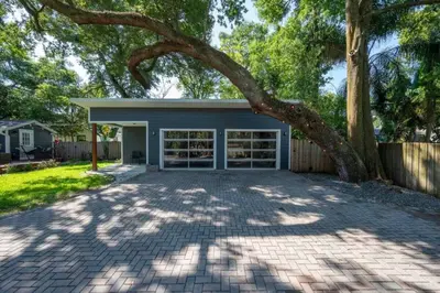 a house with a tree in front of a driveway at Massive 3 bedroom with large backyard in Orlando