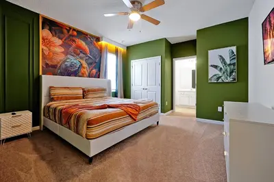 a bedroom with green walls and a bed with a painting at Luxury and Sophisticated 15 BR ensuite in Kissimmee