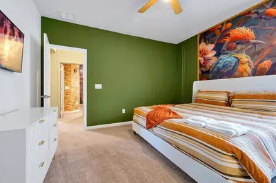 a green bedroom with a bed and a painting of a bird at Luxury and Sophisticated 15 BR ensuite in Kissimmee