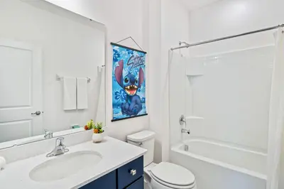 a white bathroom with a sink and a toilet and a tub at Upstay 15BR Villa w Games Room, Pool & Cinema in Kissimmee