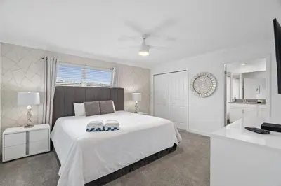 a white bedroom with a bed and a bathroom at Refúgio Incrível a 10 Min da Disney – Storey Lake in Kissimmee