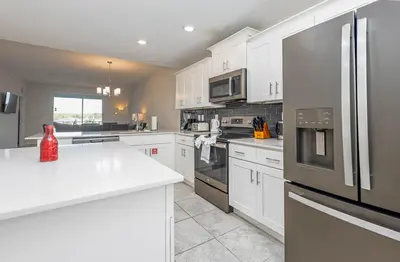 a kitchen with white cabinets and stainless steel appliances at Comfortable 2BR Condo w Lake Views in Kissimmee