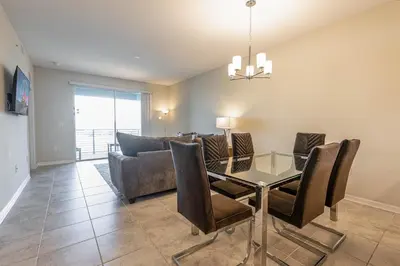 a dining room with a glass table and a couch at Comfortable 2BR Condo w Lake Views in Kissimmee