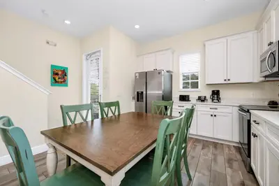 a kitchen with a wooden table and green chairs at Coral Cottage With Private Pool Near Disney With Margaritaville Resort And Island H20 Waterpark Access - 2946Sr in Orlando