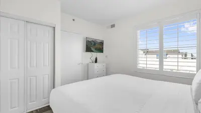 a white bedroom with a white bed and a window at Condo with Hot Tub and Pool in Orlando