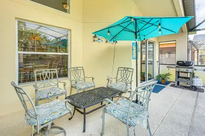 a patio table and chairs with a blue umbrella at 3 Mi to Disney World Poolside Oasis with Game Room in Kissimmee