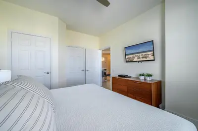a white bedroom with a bed and a wooden dresser at 4862 Cayview Avenue 408 in Orlando