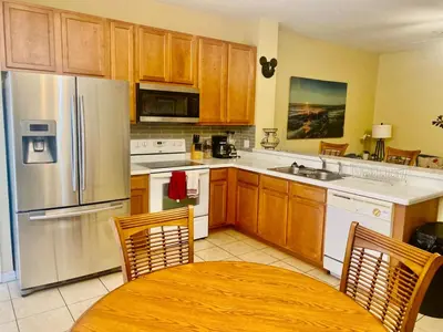 a kitchen with wooden cabinets and stainless steel appliances at Paraíso Magico Getaway 5152 in Kissimmee