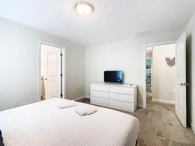 a white bedroom with a bed and a tv at Amazing 5BR Townhouse near Disney - Private Pool in Kissimmee