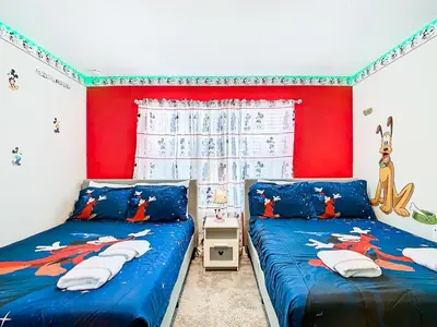 a bedroom with two beds and a red wall at Amazing 5BR Townhouse near Disney - Private Pool in Kissimmee