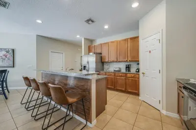 a kitchen with a bar with chairs and a refrigerator at The Hearth Home - 4 Suites in Kissimmee