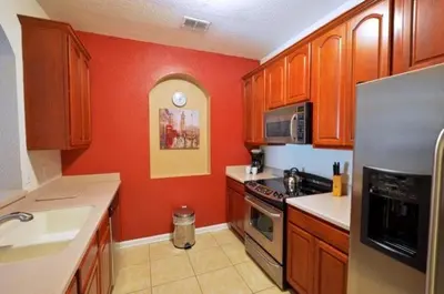a kitchen with red walls and wooden cabinets at 2 Bedroom private lakeview by Conference Center and Epic Universe walking distance in Orlando
