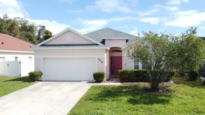 a white house with a garage at Walk to Silver Spurs Rodeo and Heritage Park home in Kissimmee