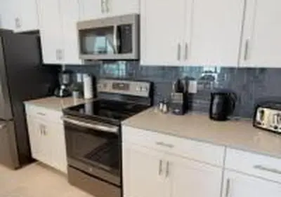a kitchen with white cabinets and a stove top oven at 4826 LL - Storey Lake Dream 4BR Pool Home Near Disney in Kissimmee