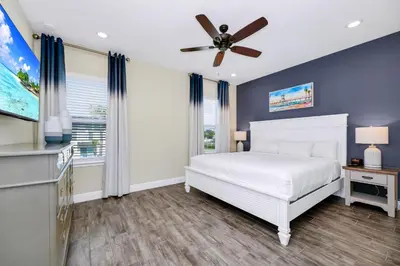 a bedroom with a white bed and a ceiling fan at Blue Sky Hideaway Villa Near Disney With Margaritaville Resort & Island H20 Waterpark Access - 2921Cs in Orlando