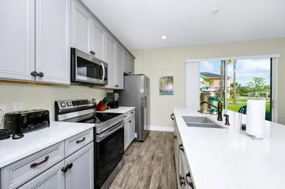 a kitchen with white cabinets and a stainless steel refrigerator at Blue Sky Hideaway Villa Near Disney With Margaritaville Resort & Island H20 Waterpark Access - 2921Cs in Orlando