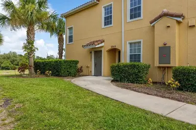 a house with a palm tree and a sidewalk at Charming 3-Bedroom Home in Gated Oakwater Resort in Orlando
