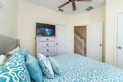 a bedroom with a bed with blue pillows and a tv at MSW2505 Windsor Hills 3 Bedroom Private Pool Townhome in Orlando
