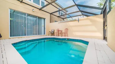 a swimming pool with two chairs and a table at OP7652 Windsor Hills 3 Bedroom Private Pool Townhome in Orlando