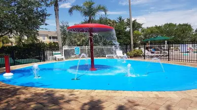 two people playing in a pool with an umbrella at Windsor Palm 3 bed Condo in Kissimmee
